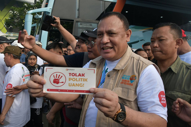 Ketua KPK Firli Bahuri (tengah) memegang stiker tolak politik uang saat road show bus KPK pada acara Hari Bebas Kendaraan Bermotor (HBKB) di Bekasi, Jawa Barat, Minggu (18/6/2023). Foto: Fakhri Hermansyah/ANTARA FOTO