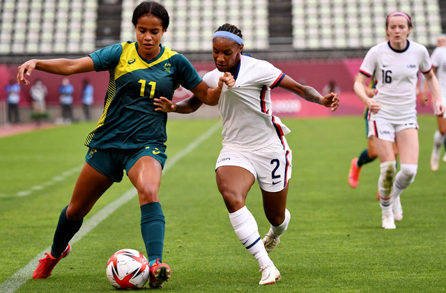 Penyerang Australia Mary Fowler (Kiri) duel dengan bek AS Crystal Dunn (Tengah) selama pertandingan sepak bola putaran pertama grup G wanita Olimpiade Tokyo 2020 antara AS dan Australia di Stadion Ibaraki Kashima pada 27 Juli 2021. Foto: Shinji Akagi/AFP