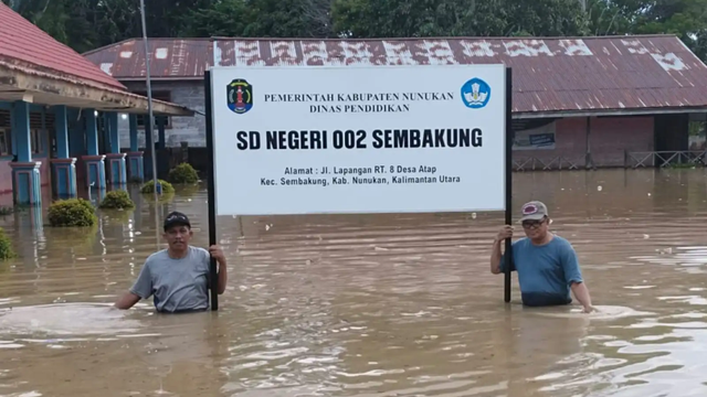 Warga berfoto di halaman SD 002 Sembakung yang tergenang banjir. Foto: HO-BPBD Kaltara/Antara