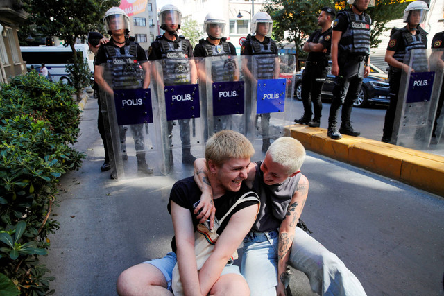 Peserta parade duduk di depan petugas polisi saat anggota komunitas LGBT+ Turki berkumpul untuk parade, yang dilarang oleh otoritas setempat, di pusat Istanbul, Turki, Minggu (25/6/2023). Foto: Dilara Senkaya/Reuters