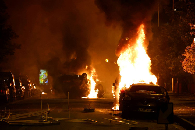 Kendaraan yang terbakar selama bentrokan antara pengunjuk rasa dan polisi, setelah kematian Nahel, seorang remaja berusia 17 tahun yang dibunuh oleh seorang petugas polisi Prancis, di Nanterre, pinggiran Paris, Prancis, Rabu (28/6/2023). Foto: Stephanie Lecocq/REUTERS 
