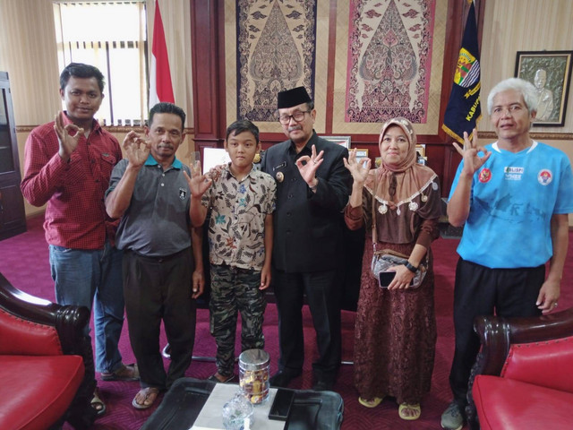 Anak tukang bangunan bernama Andika Putra (12 tahun) bersama keluarga dan pelatih pribadinya berpose dengan Bupati Cirebon, H. Imron usai meminta doa dan dukungan. Foto : Tarjoni