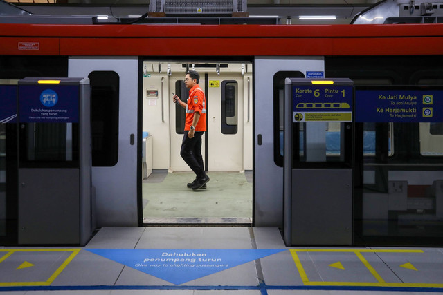 Pekerja melintasi Kereta ringan atau Light Rail Transit (LRT) Jabodebek di Stasiun LRT Dukuh Atas, Jakarta, Kamis (6/7/2023). Foto: Aditia Noviansyah/kumparan