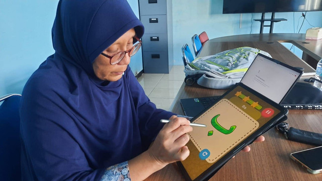 Dr Eng Nanik Suciati SKom MKom saat mempraktikkan menggunakan aplikasi Pembelajaran Huruf Hijaiyah yang dikembangkan.