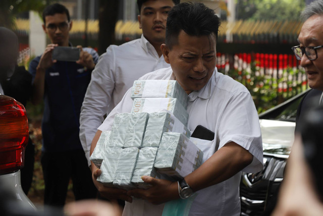 Tim kuasa hukum terdakwa korupsi BTS Kominfo, Irwan Hermawan membawa uang dalam bentuk dolar AS ke Kejagung, Jakarta, Kamis (13/7/2023). Foto: Dicky Adam Sidiq/kumparan