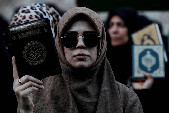 Sejumlah wanita menggelar rasa sambil membawa Al-Quran saat di luar Konsulat Jenderal Swedia di Istanbul, Turki pada Minggu (30/7/2023). Foto: Dilara Senkaya/Reuters