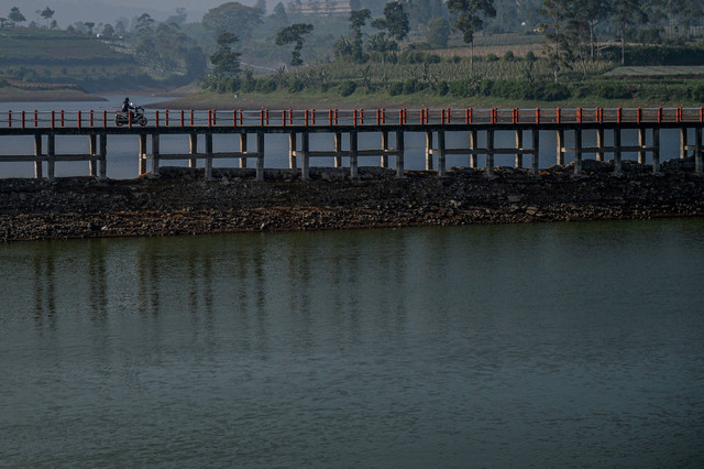 Pengendara motor melintasi jembatan di Situ atau Danau Cileunca di Pangalengan, Kabupaten Bandung, Jawa Barat, Sabtu (5/8/2023). Foto: Raisan Al Farisi/Antara Foto