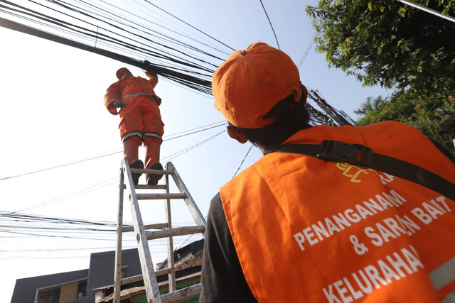 Petugas Penanganan Prasarana dan Sarana Umum (PPSU) atau Pasukan Oranye merapikan kabel yang semrawut di Jalan Siaga Raya, Jakarta, Minggu (6/8/2023). Foto: Dicky Adam Sidiq/kumparan