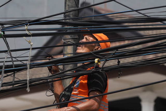 Petugas Penanganan Prasarana dan Sarana Umum (PPSU) atau Pasukan Oranye  merapikan kabel yang semrawut di Jalan Siaga Raya, Jakarta, Minggu (6/8/2023). Foto: Dicky Adam Sidiq/kumparan