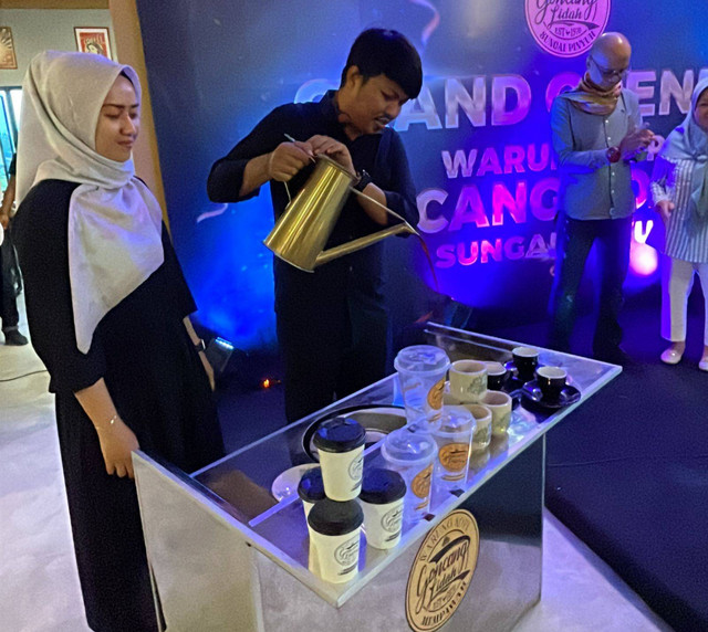 Pengelola Warkop Goncang Lidah, Dirgantara Dewo, menuangkan kopi untuk kedua orang tua dan mertuanya, saat grand opening Warkop Goncang Lidah 3 Sungai Pinyuh. Foto: Leo Prima/Hi!Pontianak
