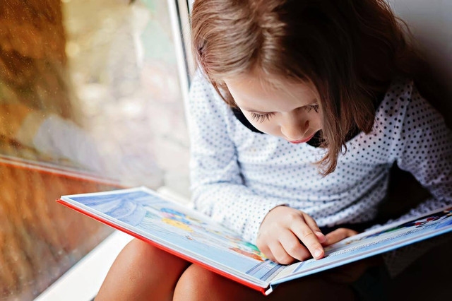 Ilustrasi Anak Membaca. Sumber: https://www.shutterstock.com/id/image-photo/toddler-girl-book-near-window-528426013 