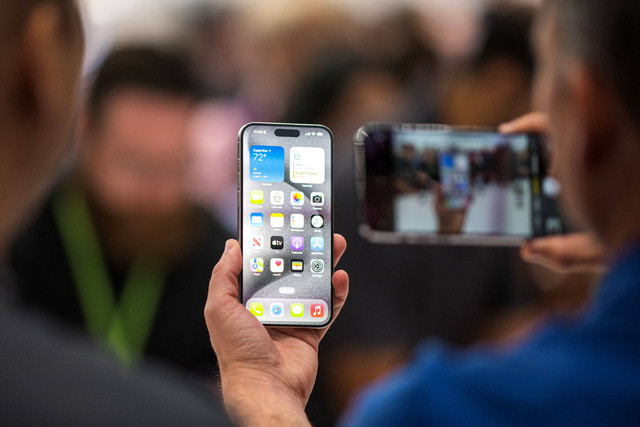 Pengunjung mencoba Apple iPhone 15 baru, dengan pengisi daya USB-C pesanan UE, ditampilkan di antara produk baru lainnya saat acara peluncuran di Apple Park di Cupertino, California, Selasa (12/9/2023). Foto: Nic Coury / AFP