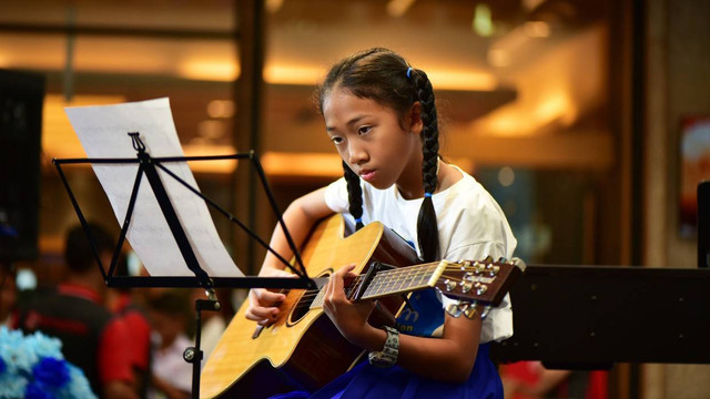 Seorang wanita bermain gitar. Foto: meesilpa sornsing/Shutterstock.