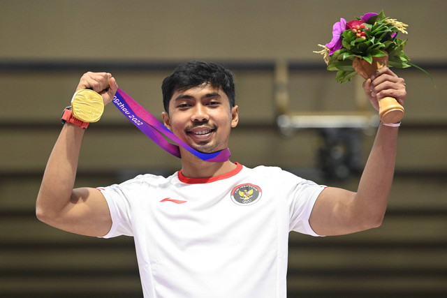 Petembak Muhammad Sejahtera Dwi Putra menunjukkan medali emasnya usai upacara penghargaan pemenang final 10 meter running target mixed run Asian Games 2022 di Fuyang Yinhu Sports Centre, Hangzhou, China, Selasa (26/9/2023). Foto: M Risyal Hidayat/ANTARA FOTO
