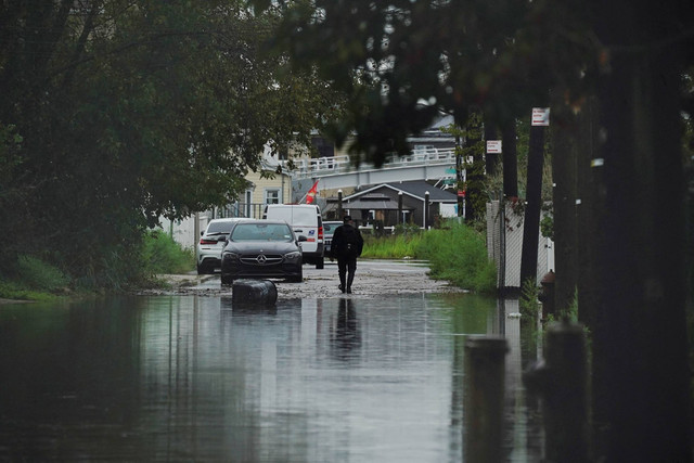 Seorang warga berjalan melewati banjir besar di lingkungan Pantai Hamilton di wilayah Queens di New York City, AS, Jumat (29/9/2023). Foto: Bing Guan/REUTERS