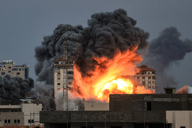 Api dan asap membubung di atas gedung-gedung selama serangan udara Israel di Kota Gaza, Sabtu (7/10/2023).  Foto: MAHMUD HAMS/AFP