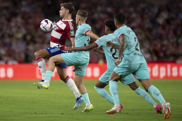 Lucas Boye (kiri) berduel dengan Fermin Lopez dalam pertandingan Liga Spanyol 2023/24 antara Granada vs Barcelona di Stadion Los Carmenes, Granada, Spanyol, pada Senin (9/10). Foto: Jorge Guerrero/AFP