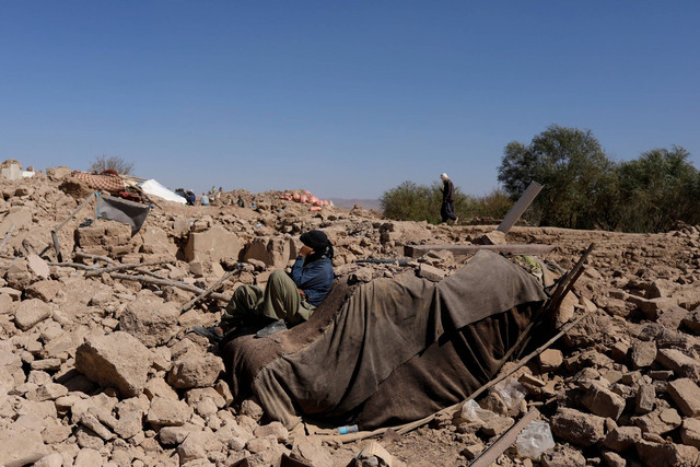 Seorang pria Afghanistan duduk melewati rumah yang rusak pasca gempa baru-baru ini di Afghanistan, Senin (9/10/2023). Foto: Ali Khara/REUTERS
