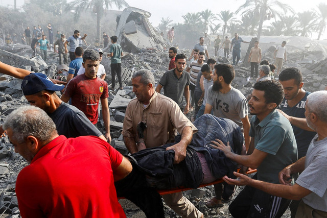 Warga Palestina membawa korban di lokasi serangan Israel terhadap rumah-rumah, di Khan Younis di selatan Jalur Gaza, Rabu (11/10/2023). Foto: Ibraheem Abu Mustafa/REUTERS