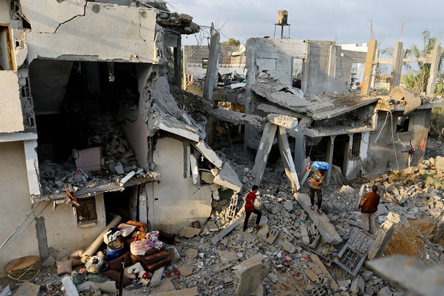 Warga Palestina membawa barang-barang di dekat rumah mereka yang rusak akibat serangan Israel, di Khan Younis di selatan Jalur Gaza, Rabu (11/10/2023). Foto: Ibraheem Abu Mustafa/REUTERS