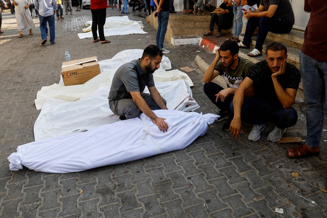 Keluarga dan kerabat berduka di samping jenazah warga Palestina yang tewas dalam serangan Israel, di sebuah rumah sakit di Kota Gaza, Rabu (11/10/2023). Foto: Mohammed Salem/REUTERS