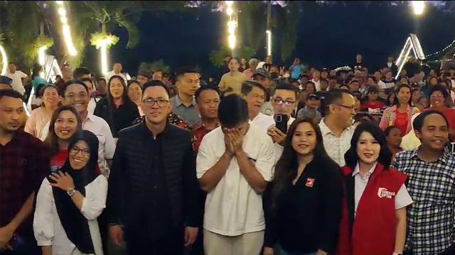 Kaesang Pangarep tertunduk dan menutup wajahnya dengan kedua tangan, saat MC meminta agar peserta yang berfoto bersama mengepalkan tangan dan menerikkan nama Jokowi.
