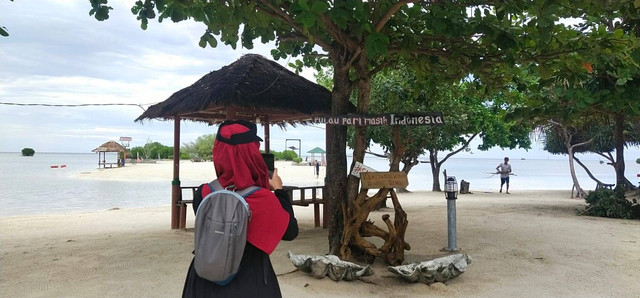 Seorang wisatawan sedang mengabadikan keindahan Pantai Pasir Perawan Pulau Pari. Foto: dok pribadi.