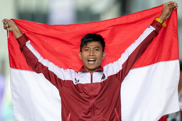 Pelari putra Indonesia Saptoyogo Purnomo berpose dengan Bendera Merah Putih usai meraih medali emas nomor lari 400 meter T37 Asian Para Games 2022 di Hangzhou Olympic Sports Centre Stadium, Hangzhou, China, Senin (23/10/2023). Foto: NPC Indonesia/Josua Yulianto/Antara Foto