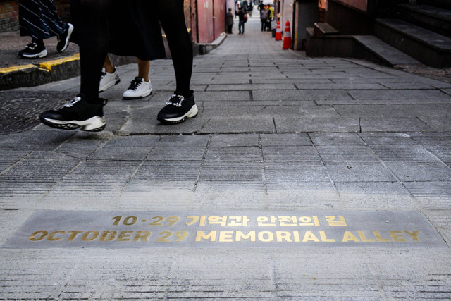 Pejalan kaki berjalan melewati tulisan yang baru diresmikan bertuliskan 29 Oktober Memorial Alley di Itaewon, Seoul, Korea Selatan, Rabu (25/10/2023). Foto: Anthony Wallace/AFP