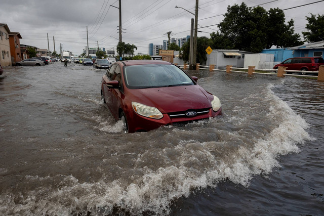 Pengendara mobil melewati air banjir di Hialeah, Florida, AS, Kamis (16/11/2023). Foto: Marco Bello/REUTERS