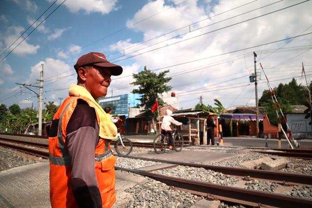 Suro mengamati perlintasan dari jauh dan bersiaga menutup palang pintu bila ada Kereta Api (KA) yang akan melintas, Dukuh Kudu rejo, Minggu (19/11/2023). (Dok. Pribadi).