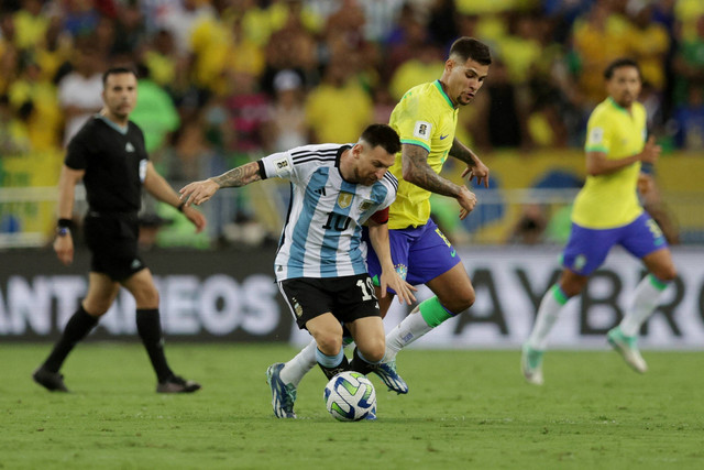 Pemain Brasil Bruno Guimaraes berebut bola dengan pemain Argentina Lionel Messi  pada pertandingan Kualifikasi Piala Dunia 2026 zona CONMEBOL di Stadion Maracana, Rio de Janeiro, Brasil, Rabu (22/11/2023). Foto: Ricardo Moraes/REUTERS