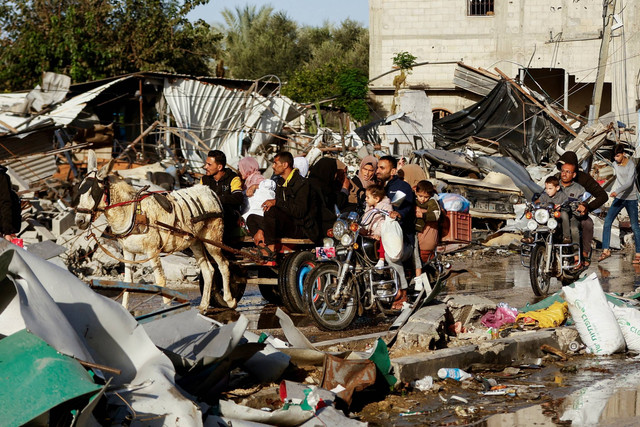 Warga Palestina menaiki kereta keledai saat mereka kembali ke rumah mereka, selama gencatan senjata sementara antara Hamas dan Israel, di Khan Younis di selatan Jalur Gaza, Jumat (24/11/2023). Foto: Ibraheem Abu Mustafa/REUTERS