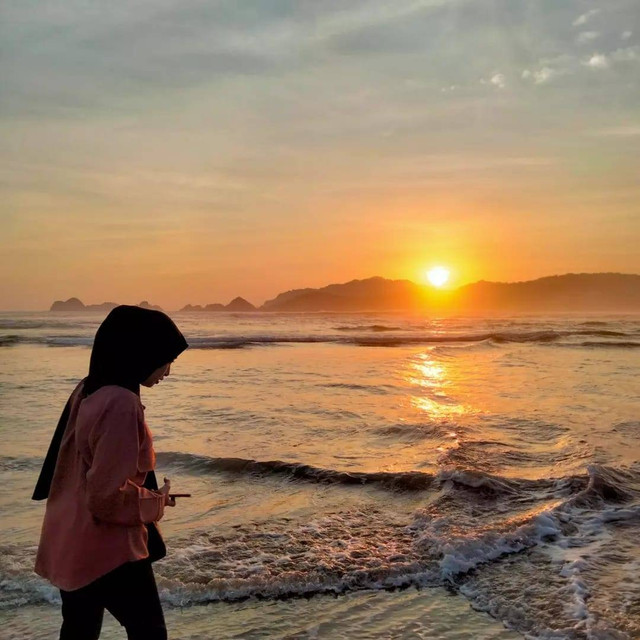 Penulis ketika menikmati suasana matahari terbenam di Pantai Pulau Merah (Sumber Foto : Foto Pribadi)