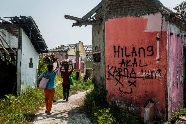 Hilang Akal - Warga mencari kayu di sekitar rumah yang sudah ditinggali pemiliknya di Kampung Susukan, Lebak, Banten. Foto: Muhammad Bagus Khoirunas/Antara Foto