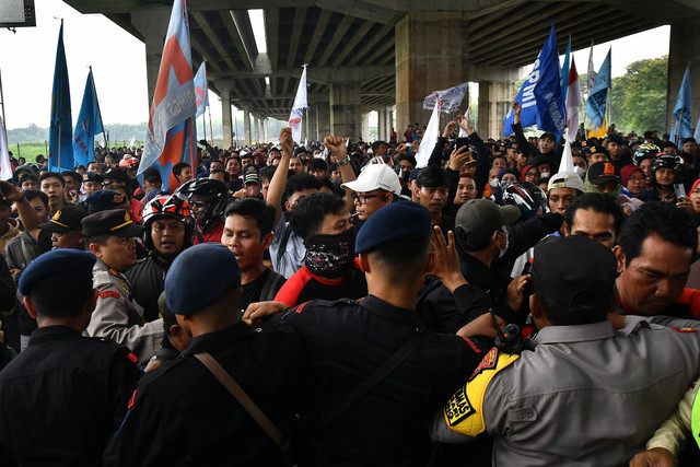 Sejumlah personel Kepolisian menahan buruh yang ingin menuju gerbang Tol Cibitung 3 di kawasan MM 2100, Kabupaten Bekasi, Jawa Barat, Kamis (30/11/2023). Foto: ANTARA FOTO/ Fakhri Hermansyah