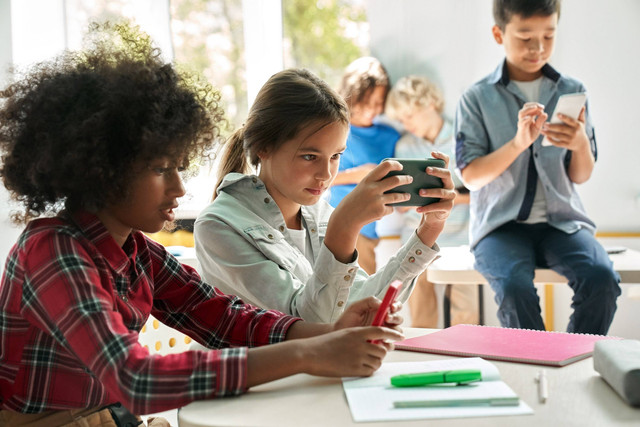 Ilustrasi anak bermain handphone di sekolah. Foto: Shutterstock