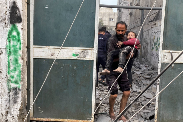 Seorang warga Palestina membawa seorang anak laki-laki yang terluka menyusul serangan Israel di sebuah rumah, setelah gencatan senjata sementara antara Hamas dan Israel berakhir, di Rafah, di selatan Jalur Gaza, Jumat (1/12/2023). Foto: Hatem Khaled/REUTERS