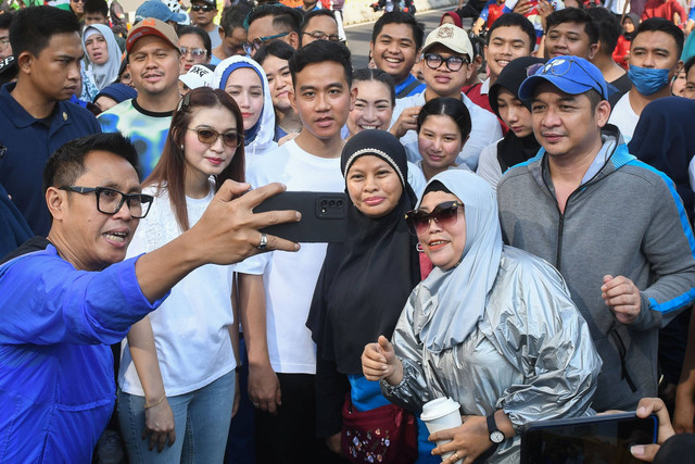 Cawapres nomor urut 2 Gibran Rakabuming Raka (tengah) bersama istrinya Selvi Ananda (kedua kiri) dan sejumlah politisi dari partai politik pengusung Gibran berswa foto dengan warga di area hari bebas kendaraan bermotor (HBKB) Jalan MH Thamrin. Foto: Aditya Pradana Putra/Antara Foto