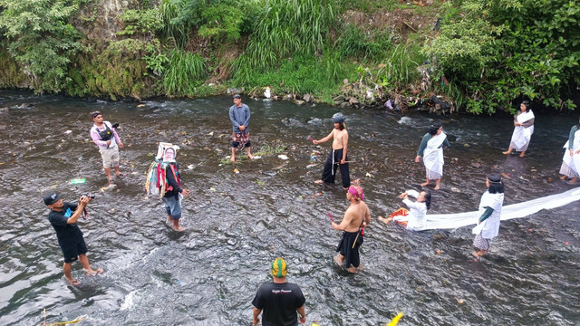 Sejumlah warga Yogyakarta yang tergabung dalam komunitas budaya Patembayan Nusantara menggelar aksi Larung Sukerta membersihkan Yogyakarta dari pengaruh jahat Ade Armando di Kali Gajah Wong, Gambiran, Kemantren Umbulharjo, Kota Yogyakarta. Foto: Arfiansyah Panji/kumparan