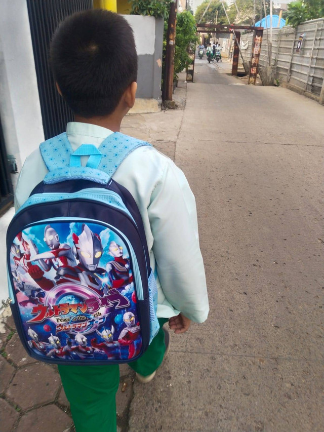 Seorang anak berangkat ke sekolah tidak ditemani oleh ayahnya yang jauh di kota lain. Photo: Dokumentasi Pribadi