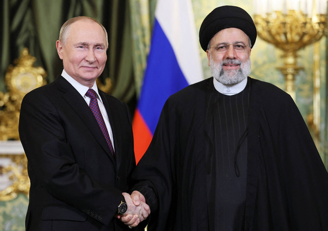 Presiden Rusia Vladimir Putin (kiri) berjabat tangan dengan Presiden Iran Ebrahim Raisi selama pertemuan mereka di Kremlin di Moskow pada 7 Desember 2023. Foto: Sergei Bobylyov / POOL / AFP