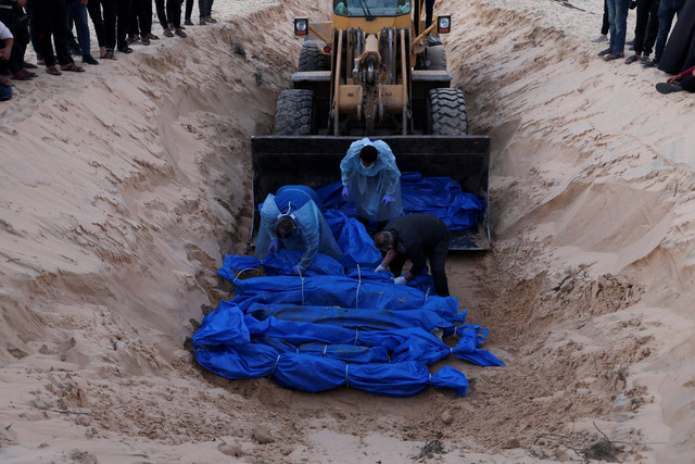 Orang-orang menguburkan warga Palestina yang terbunuh oleh serangan dan tembakan Israel, di kuburan massal di Rafah, di Jalur Gaza selatan, Selasa (26/12/2023). Foto: Ibraheem Abu Mustafa/REUTERS
