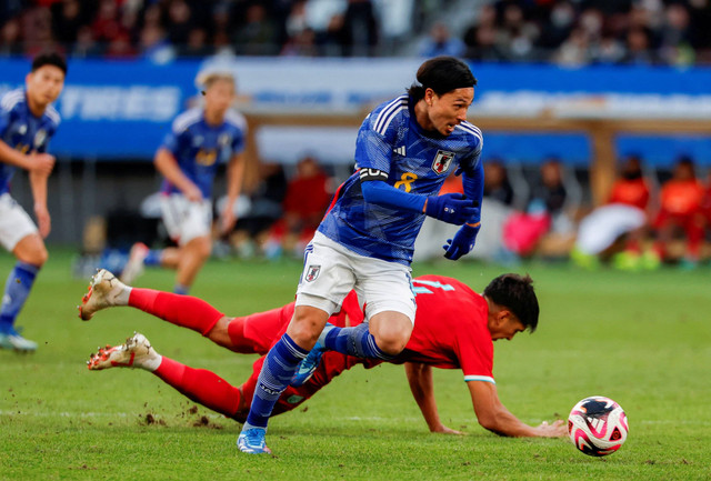 Takumi Minamino dari Jepang beraksi bersama Yusef Elias Dolah dari Thailand saat pertandingan persahabatan internasional di Stadion Nasional Jepang, Tokyo, Jepang. Foto: Issei Kato/Reuters