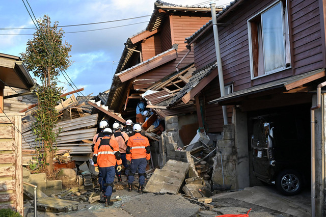 Petugas pemadam kebakaran memeriksa rumah-rumah kayu yang runtuh di Wajima, prefektur Ishikawa, Jepang pada Selasa (2/1/2024). Foto: Kazuhiro Nogi/AFP