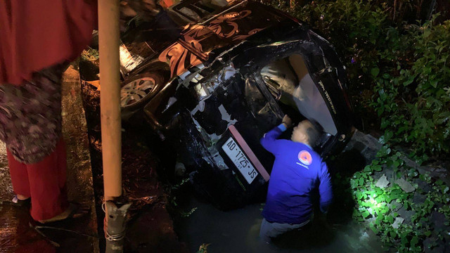 Polisi saat mengevakuasi mobil yang terlempar ke parit usai ditabrak bus. Foto: istimewa
