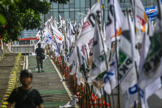 Warga melintas di samping alat peraga kampanye (APK) pemilu 2024 yang terpasang di pembatas jalur sepeda (stick cone) di kawasan Menteng, Jakarta, Senin (8/1/2024). Foto: Galih Pradipta/ANTARA FOTO