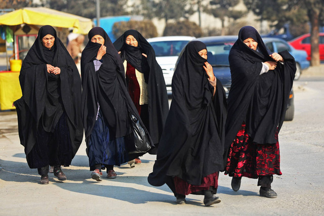 Wanita Afghanistan berburqa berjalan melalui jalan di Kabul pada 28 Desember 2022. Foto: AFP