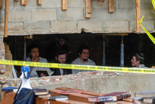 Mahasiswa Yahudi Hasid duduk di balik celah dinding sinagoga yang menuju ke terowongan yang digali mahasiswa,di New York City, AS, Senin (8/1/2024). Foto: Bruce Schaff via AP