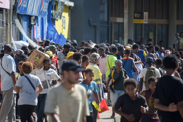 Orang-orang mengelilingi toko-toko di tengah kerusuhan di Port Moresby, Papua Nugini, pada Rabu (10/1/2024). Foto: Andrew KUTAN/AFP
